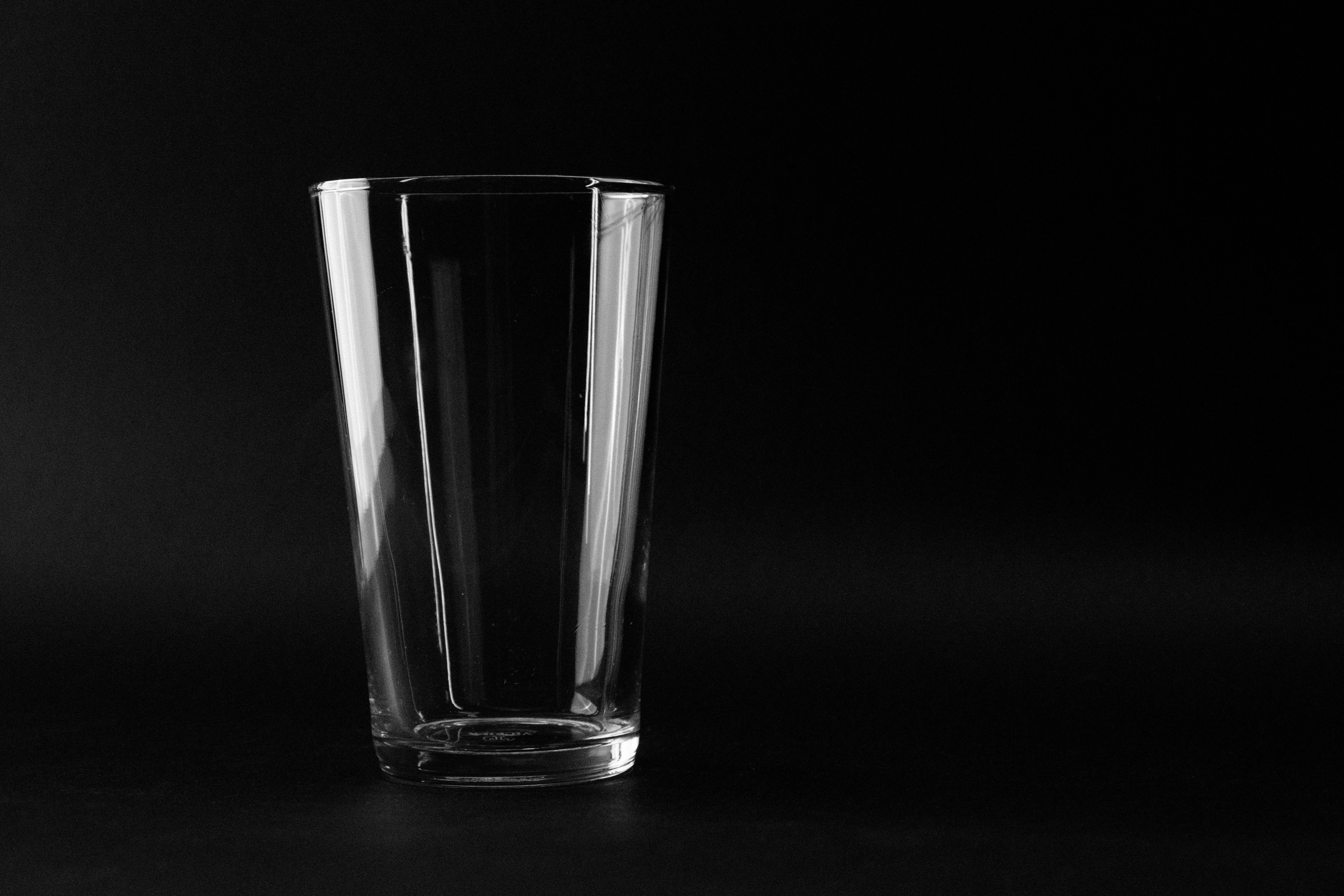 A single empty glass on a black surface, lit softly from one side.