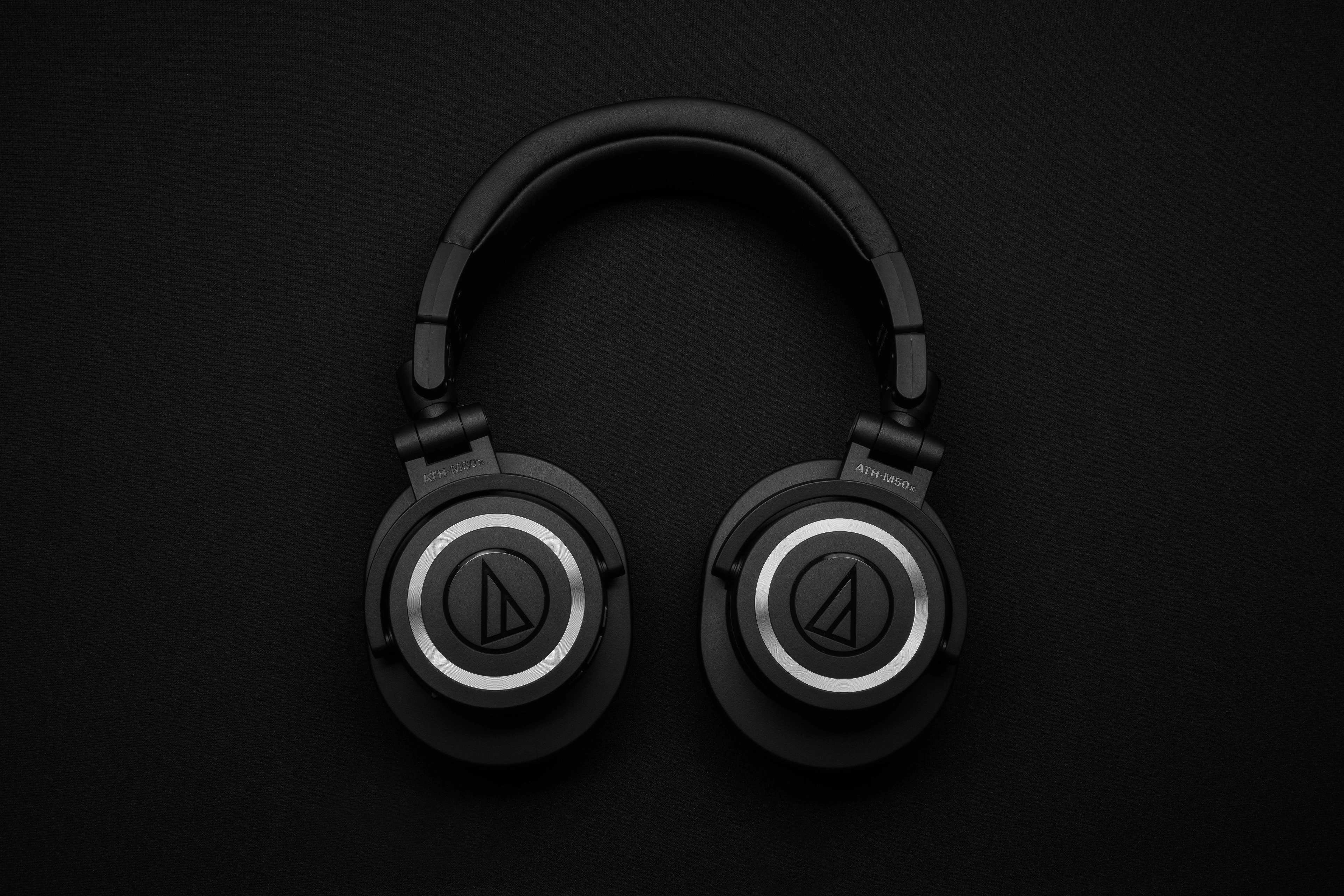 Black over-ear headphones resting on a dark surface under low side light.