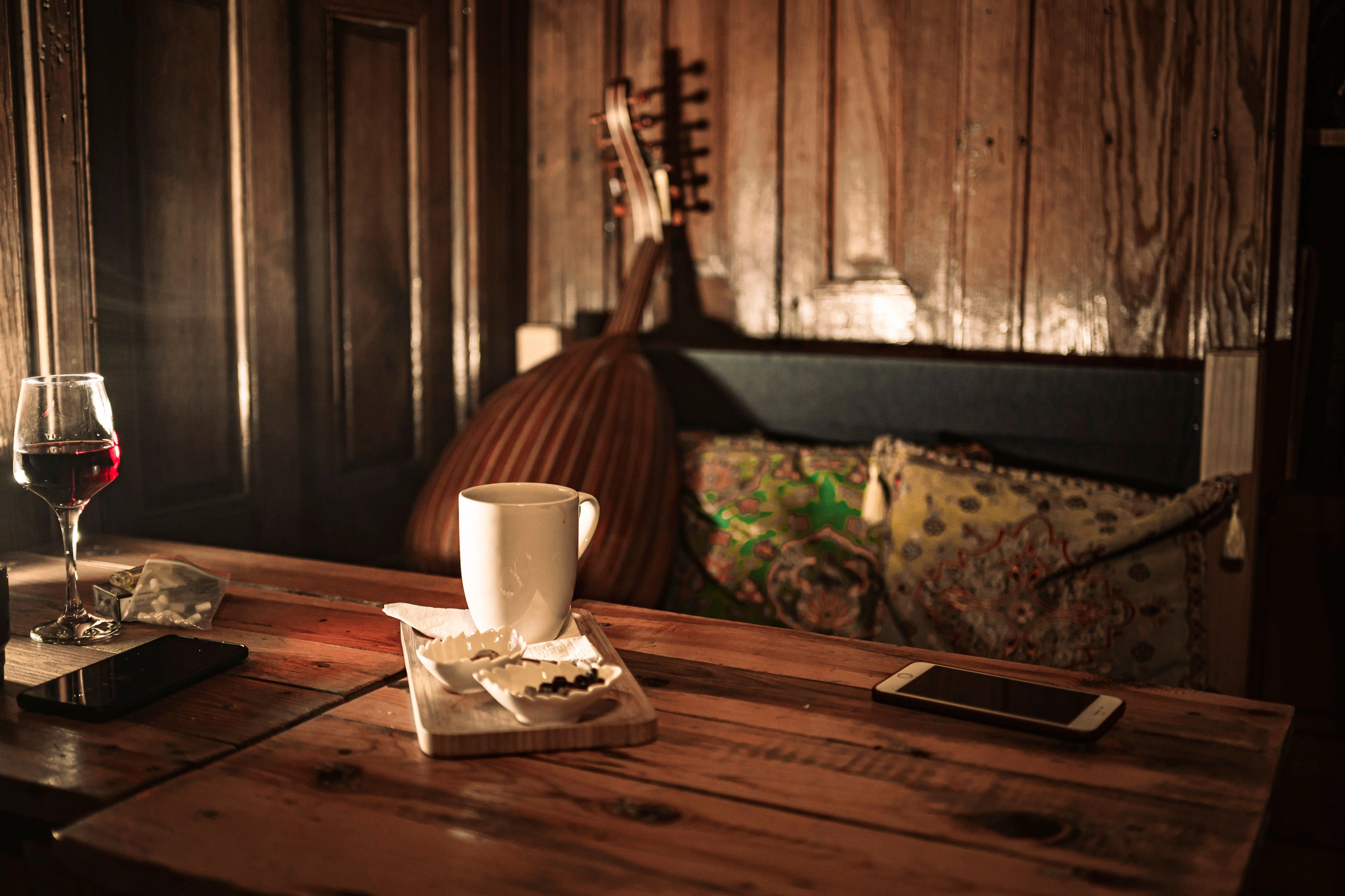 A cup and glass on a wooden table in a warm, dimly lit room.