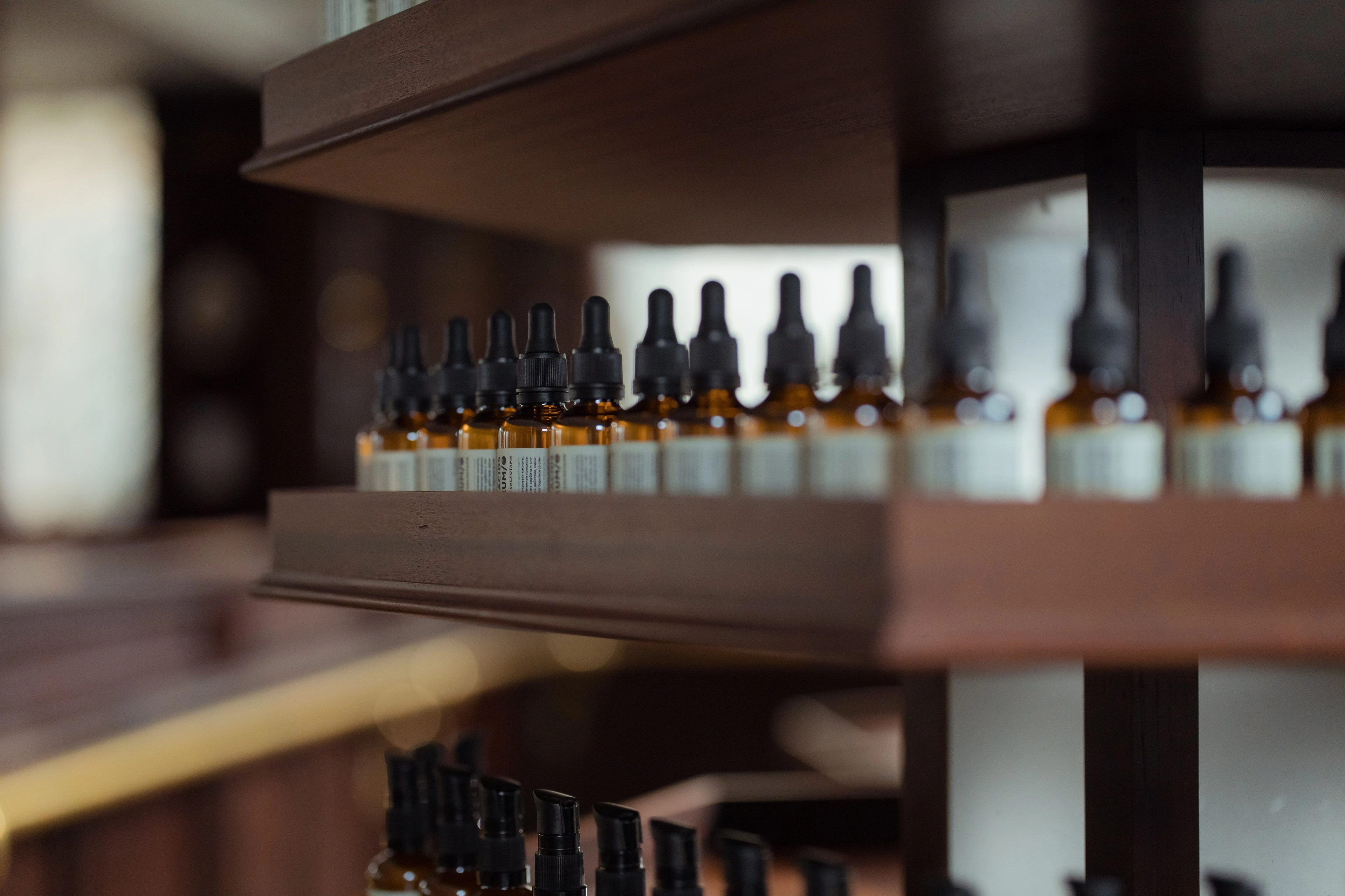 Rows of amber dropper bottles on a dark wooden shelf.