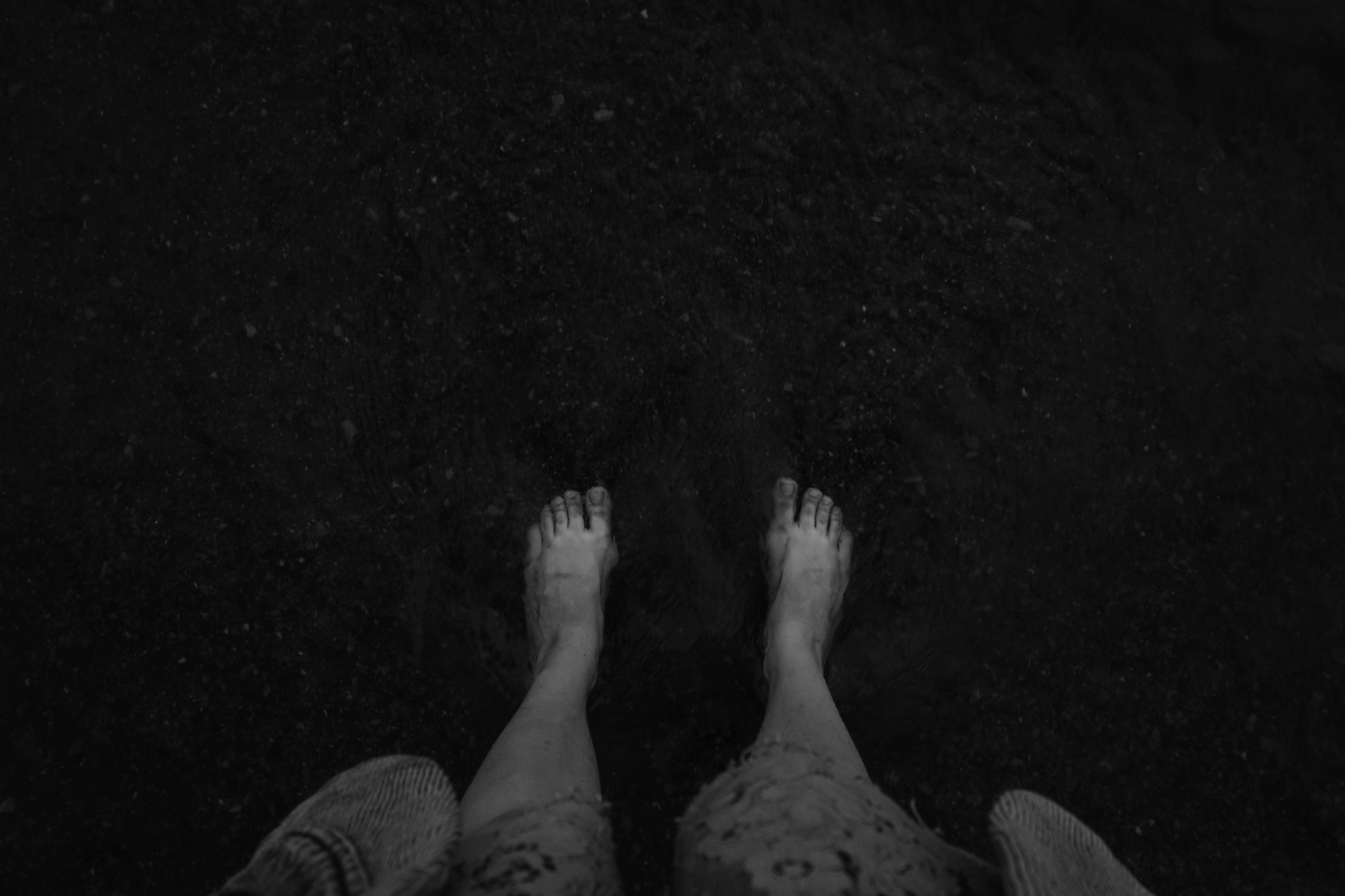 Bare feet standing on dark bare earth.
