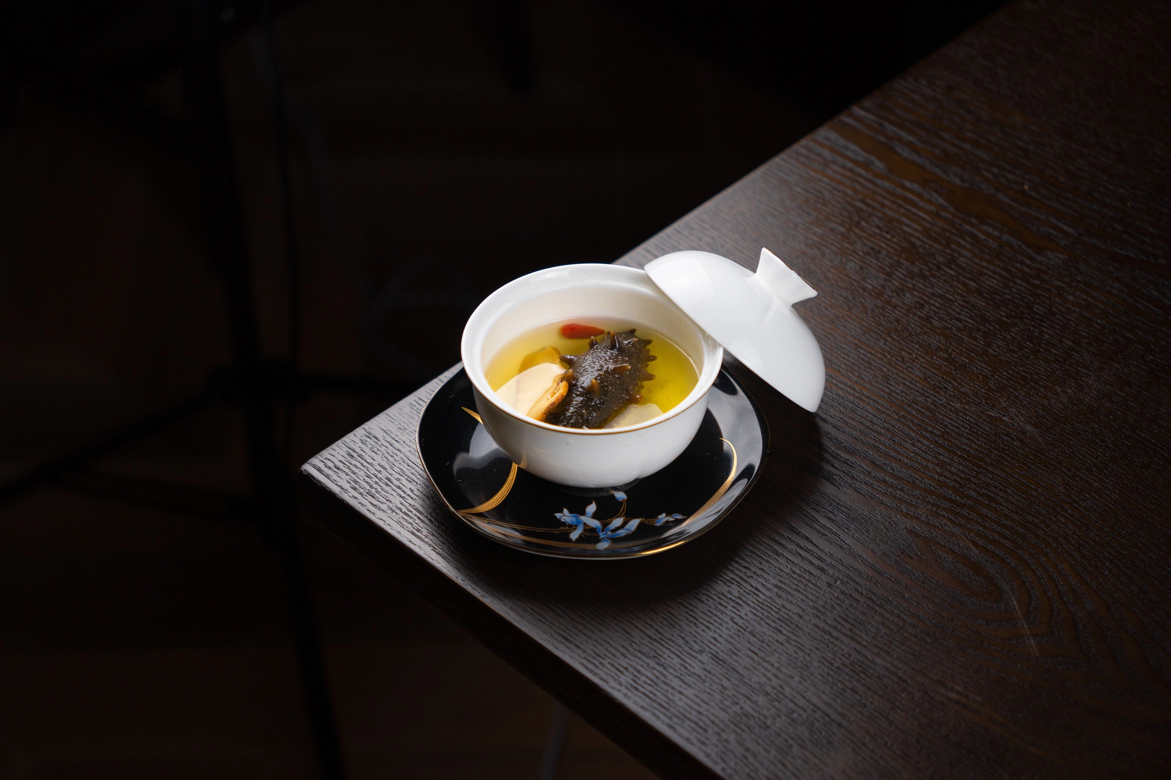 A bowl on a dark wooden table lit by warm lamplight.