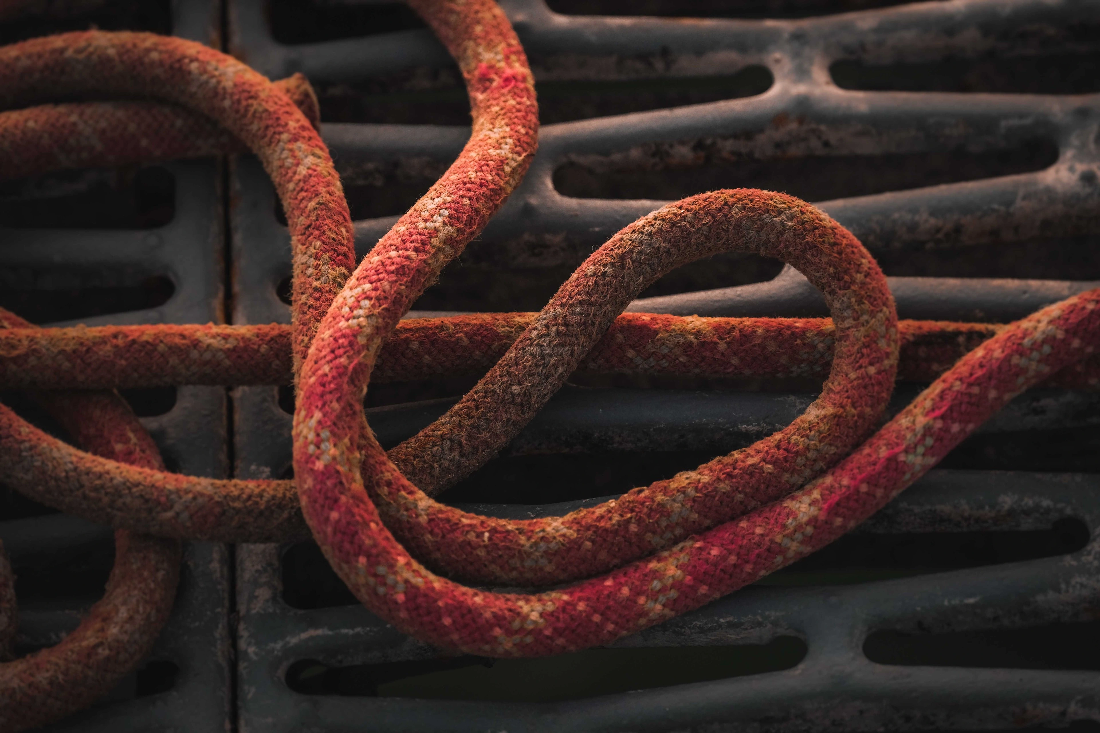 A coiled length of red rope on a dark metal grate.