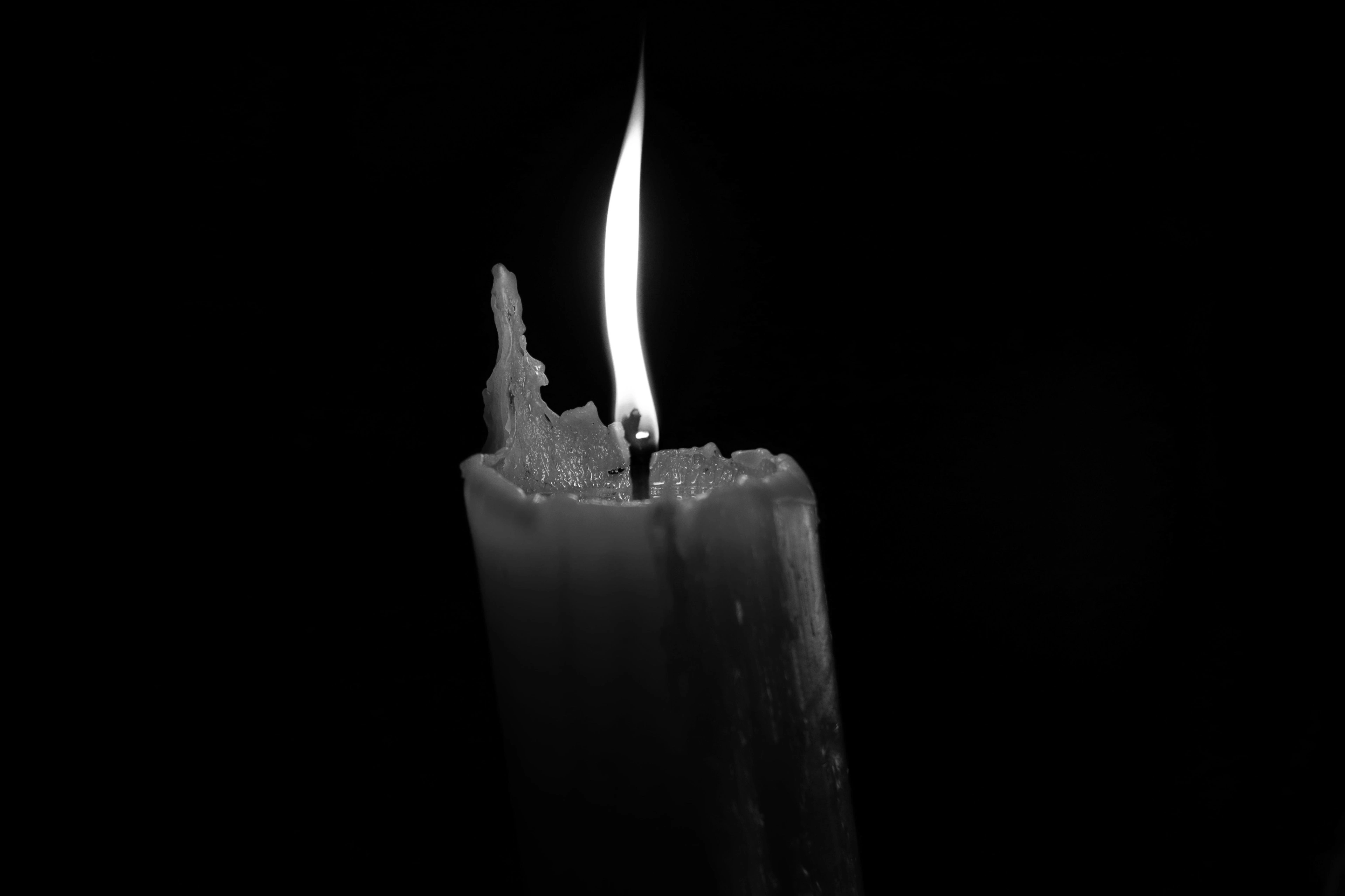 A single candle flame burning against near-total darkness.