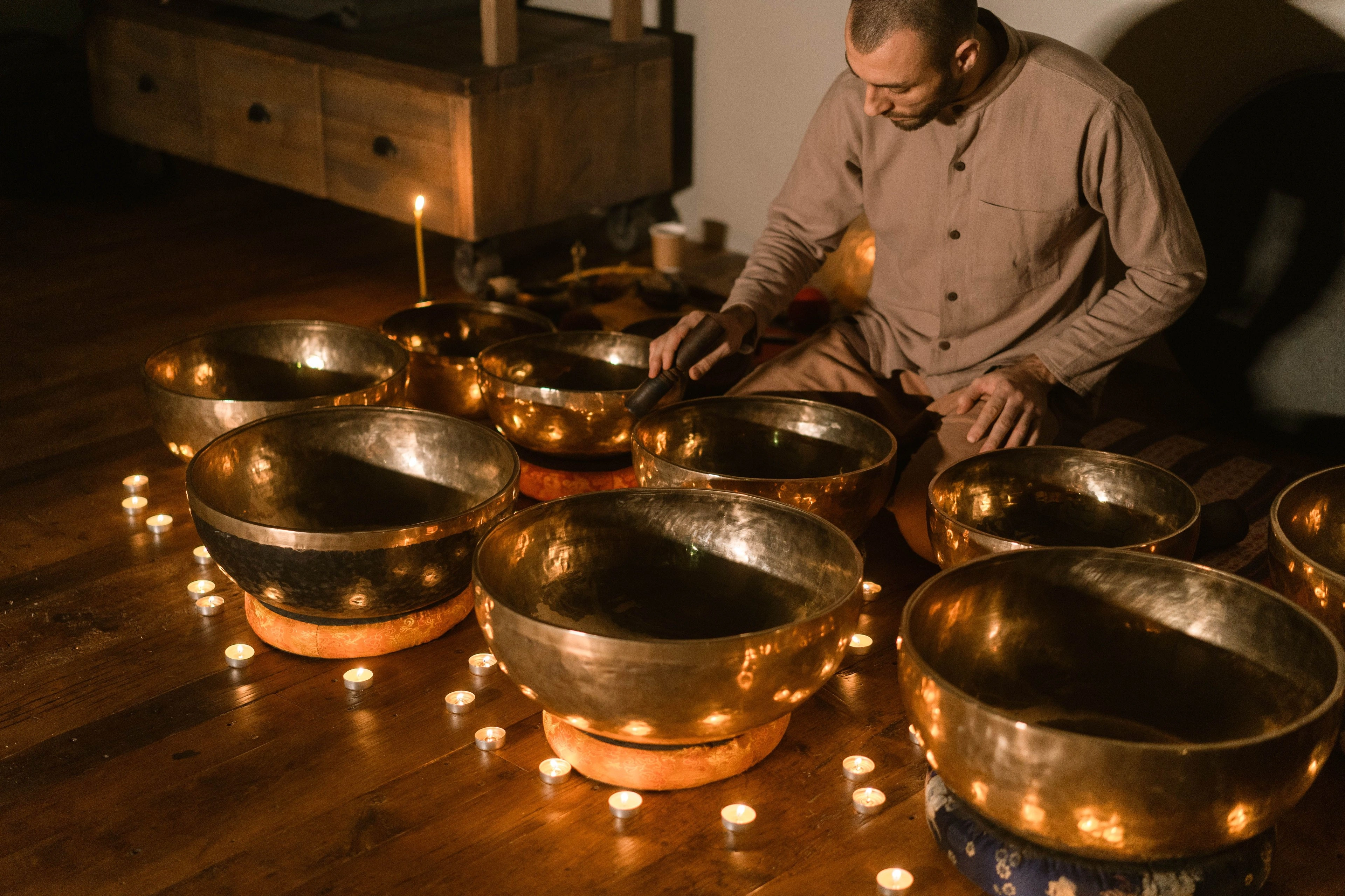 Brass singing bowls arranged in warm candlelight.