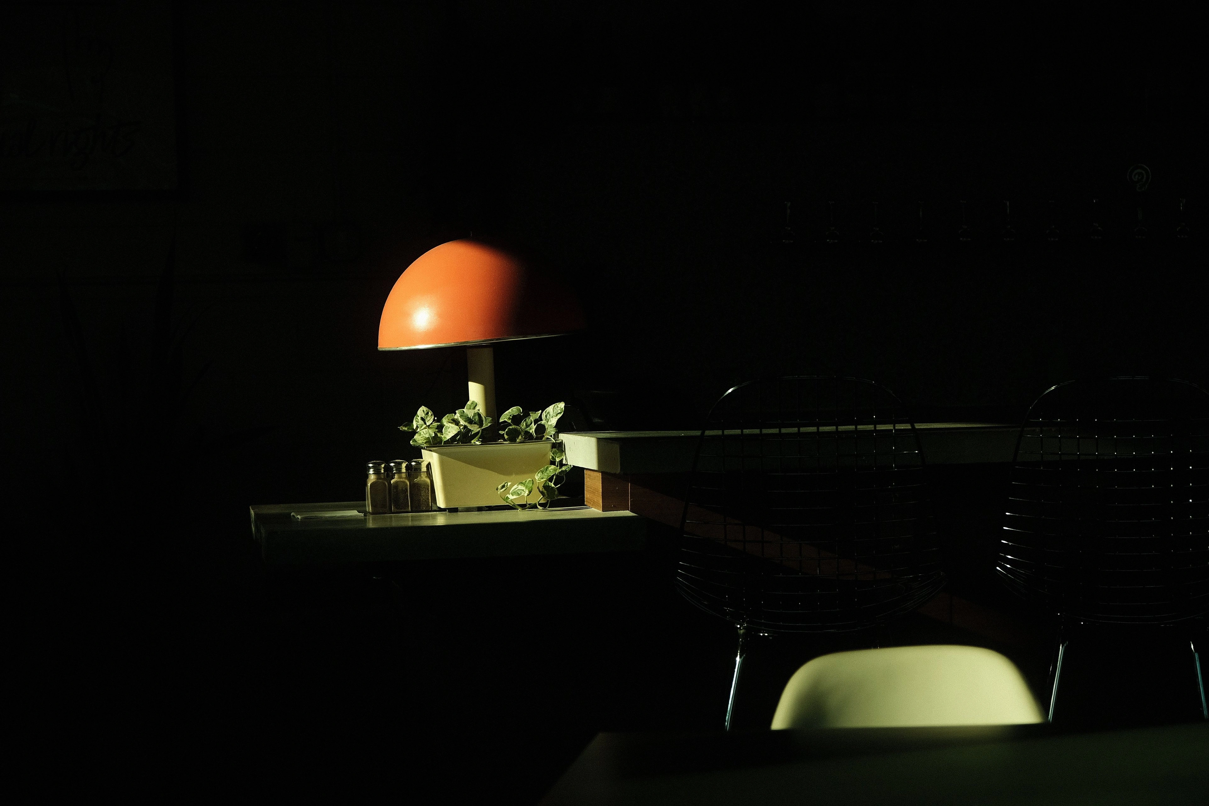 A dim room lit by a single lamp, deep shadow all around.