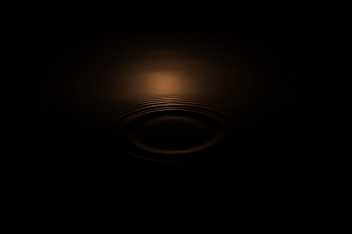 A close view of a dark still water surface with a single faint ripple spreading from the center, lit by one narrow warm light against near-black.