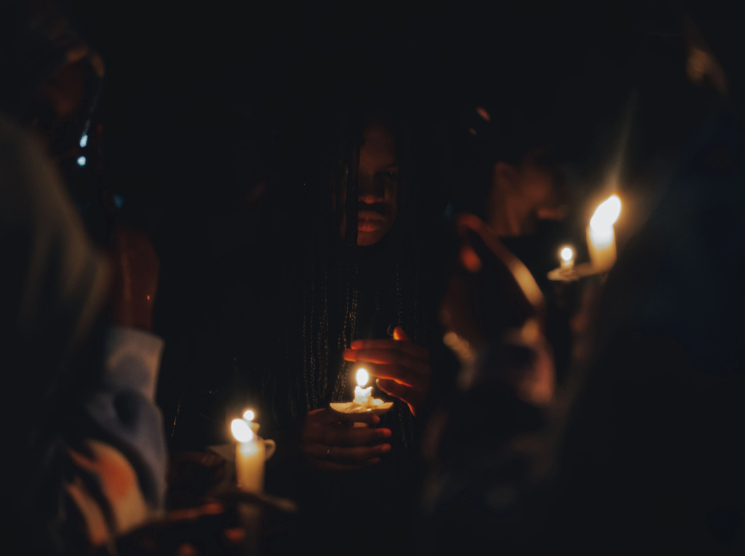 People gathered holding candles in the dark.