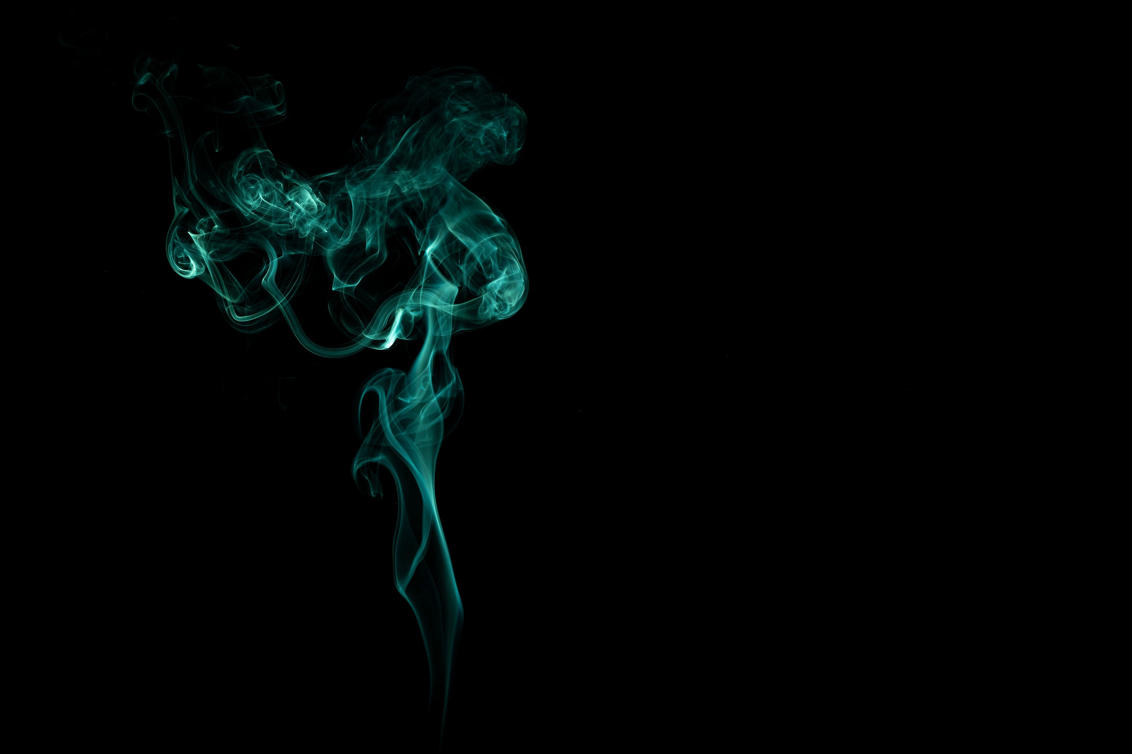 A single wisp of pale smoke curling against a black background.