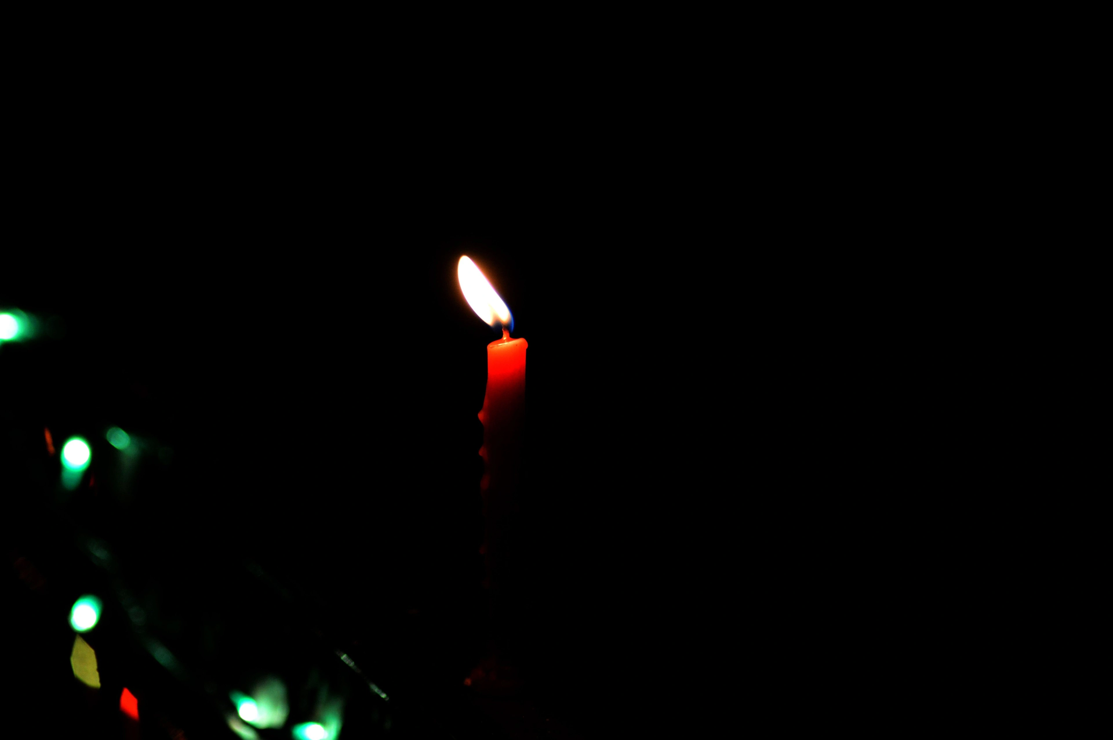A single candle flame glowing amid soft points of light in darkness.