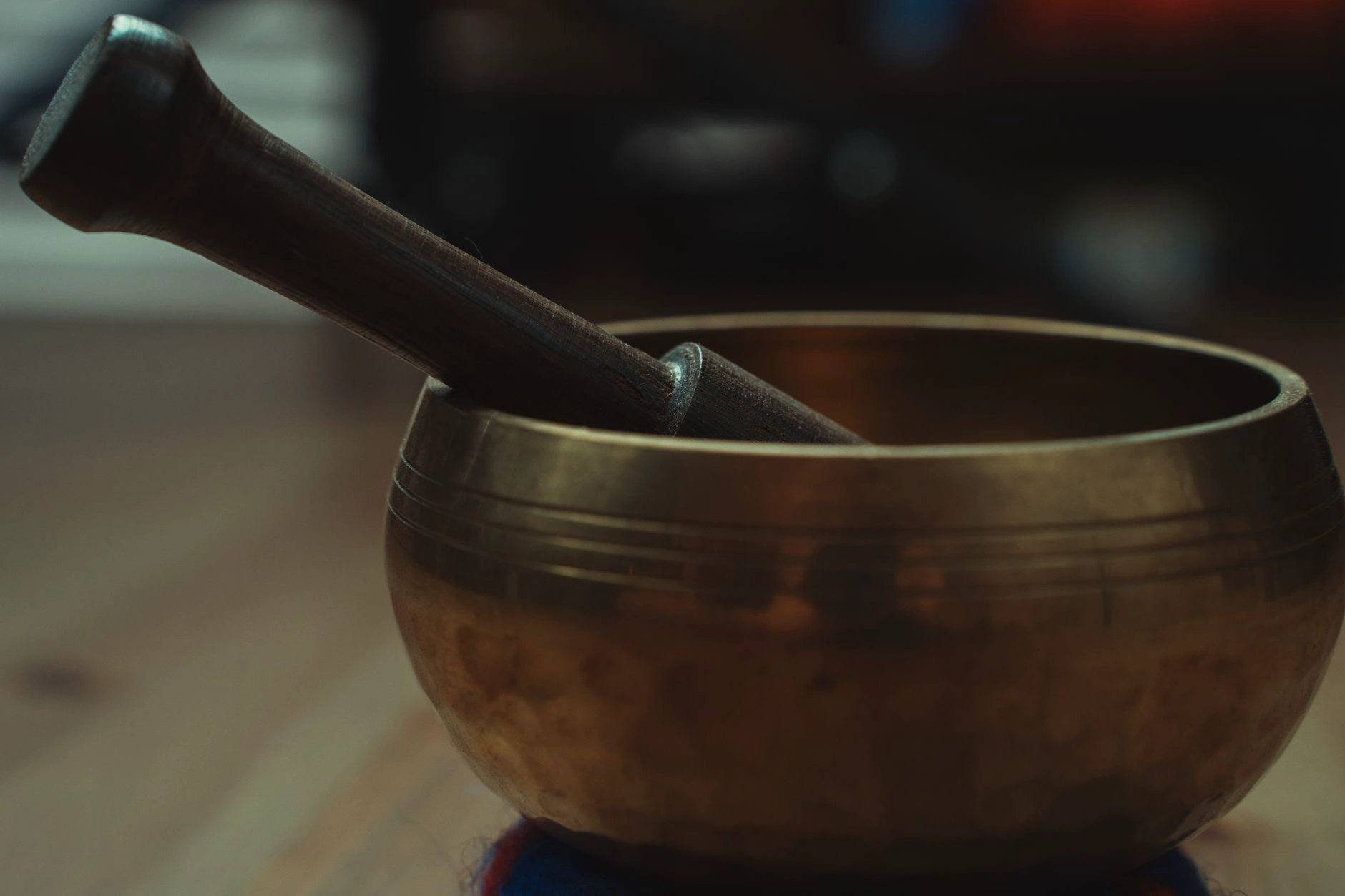 A brass singing bowl filled with water showing cymatic ripple patterns, warm gold light in a misty dark space.