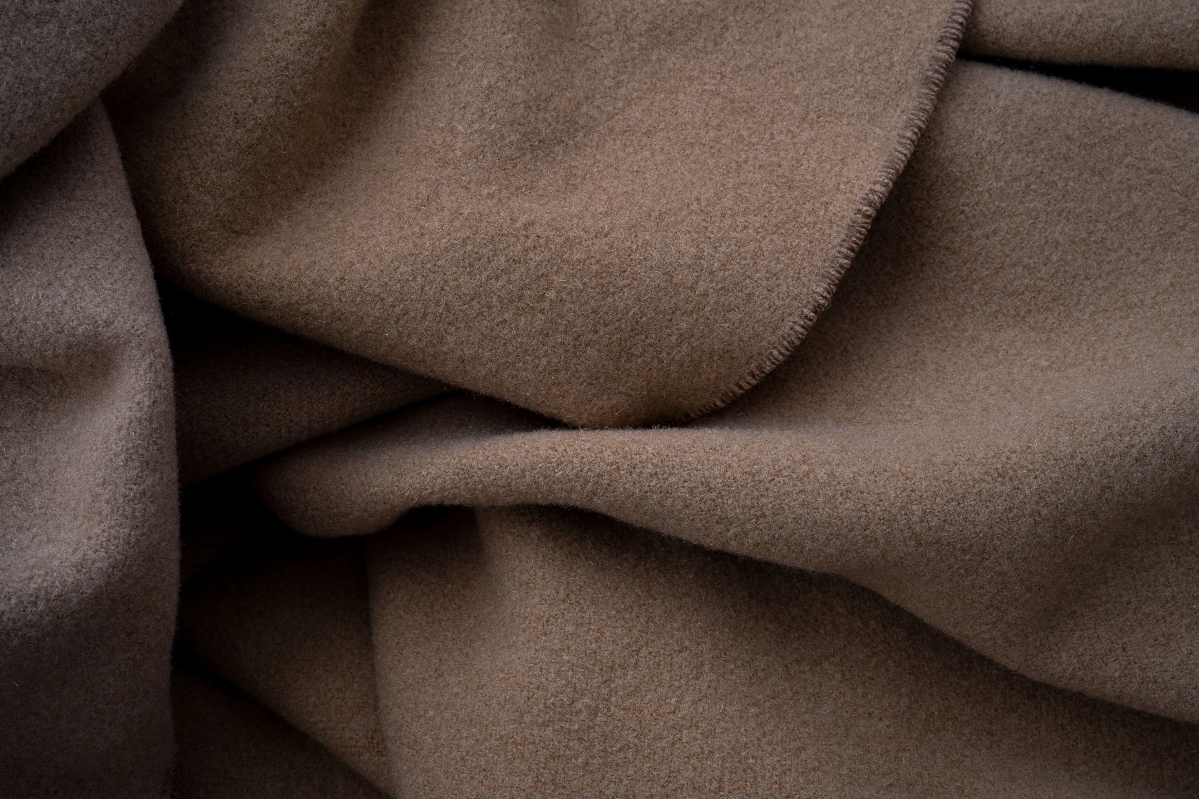 Soft folds of neutral draped fabric in low light.